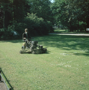 824484 Afbeelding van een medewerker van de gemeentelijke plantsoenendienst met een Locke-motorgrasmaaier in een park ...